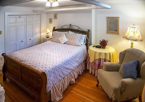 a bedroom with a bed and a chair and a table at Alexander Mansion Bed & Breakfast in Winona