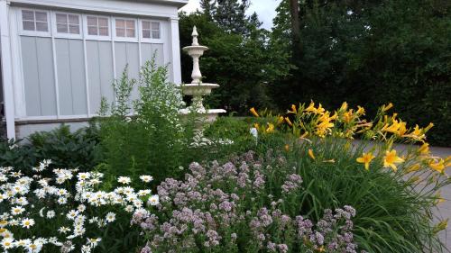 a garden with a fountain and flowers in front of a house at Alexander Mansion Bed & Breakfast in Winona