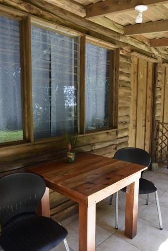 a wooden table and chairs in a room with windows at Villas Maria Luisa in Uvita