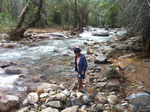 a man standing on rocks in a river at Holiyday in VGF Farm House in Dānishpet