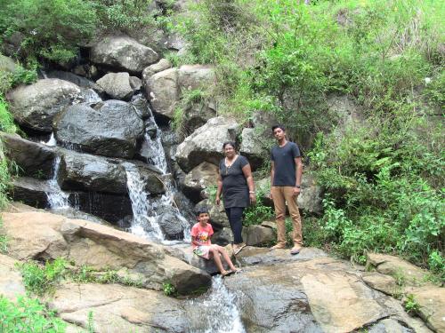 a group of people standing on rocks near a waterfall at Holiyday in VGF Farm House in Dānishpet