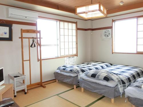 two beds in a room with two windows at Suzukisou in Kyoto