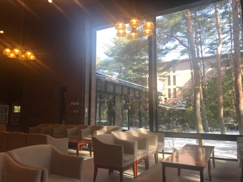 a room with chairs and tables and a large window at Jiragonno Fuji no Yakata in Narusawa