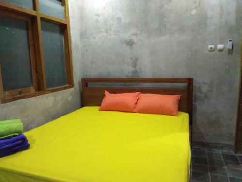 a yellow bed with a orange pillow in a room at Griyo Jagalan in Borobudur