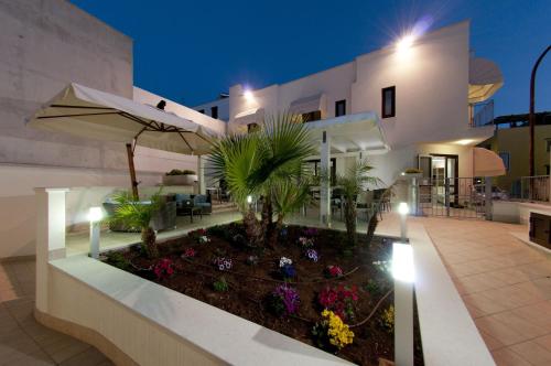 a house with a garden with flowers and an umbrella at Alaba Hotel in San Vito lo Capo