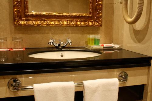 a bathroom with a sink and a mirror and towels at Gran Hotel Los Abetos in Santiago de Compostela