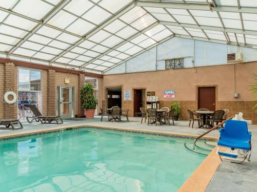 a swimming pool with an indoor patio with tables and chairs at Best Western Alamosa Inn in Alamosa