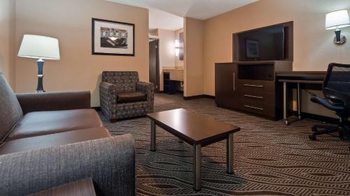 a hotel room with a couch and a desk and a television at Best Western Plus Galleria Inn & Suites in Memphis