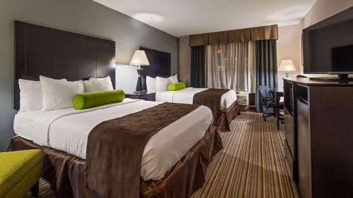 a hotel room with two beds and a flat screen tv at Best Western Plus Sunrise Inn in Nashville