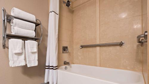 a bathroom with a tub and a shower with towels at Best Western Plus Sunrise Inn in Nashville