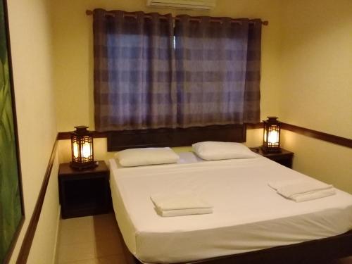 een slaapkamer met een bed met 2 lampen en een raam bij Bootshaus in Koh Lanta