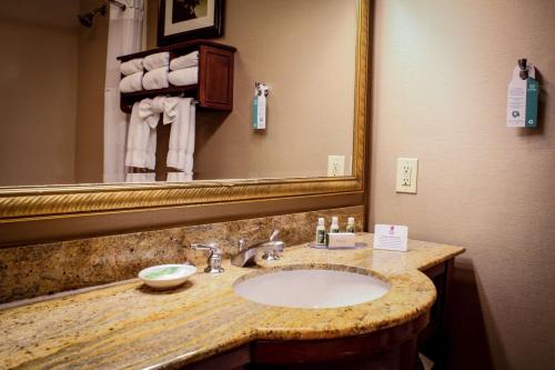Best Western Plus Arrowhead Hotel في كولتون: حمام مع حوض ومرآة كبيرة