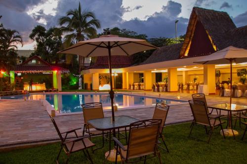 una mesa con sillas y una sombrilla junto a la piscina en Best Western Plus Hotel Terraza, en San Salvador