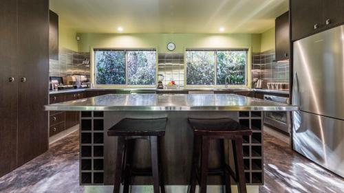 a kitchen with a large counter with stools in it at CELADON Holiday House in Palm Cove