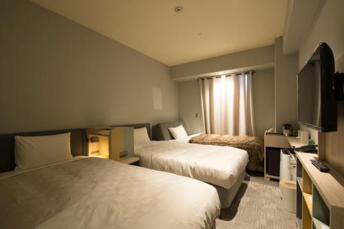 a hotel room with two beds and a flat screen tv at HOTEL FUKURACIA OSAKA-BAY in Osaka