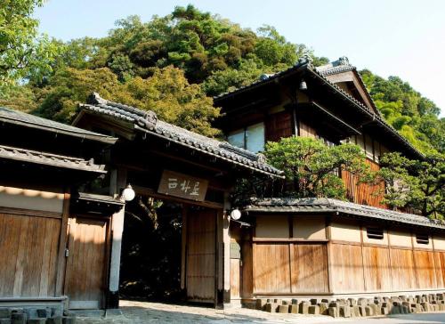 an asian style building with trees in the background at Nishimuraya Honkan in Toyooka