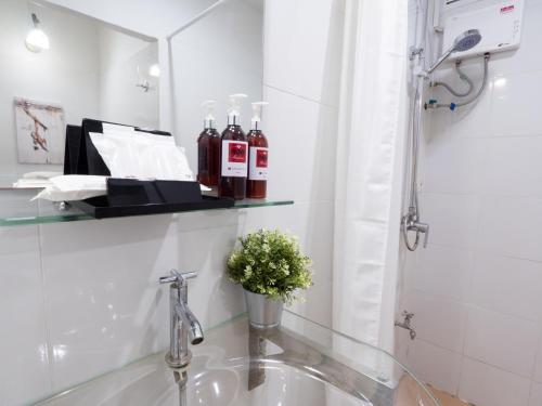 bagno con lavandino e doccia con bottiglie di vino di Pann Residence a Bangkok