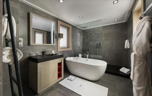 uma casa de banho com uma banheira branca e um lavatório. em Le K2 Djola em Courchevel