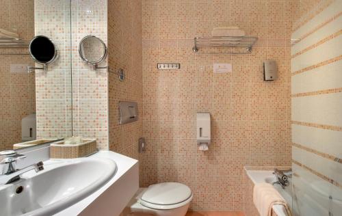 La salle de bains est pourvue d'un lavabo, de toilettes et d'une baignoire. dans l'établissement Logis Hôtel du Midi - Saint Etienne Sud, à Saint-Étienne