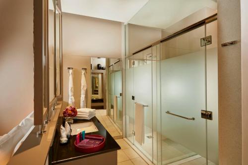 a bathroom with a walk in shower and a mirror at Sentido Heritance Negombo in Negombo