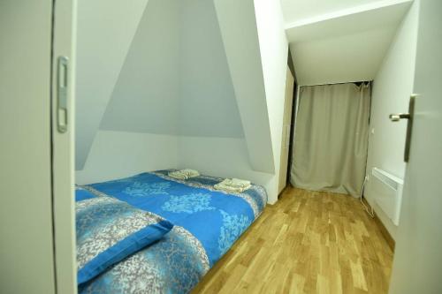 een kleine slaapkamer met een blauw bed en een houten vloer bij Dvori Apartments in Kopaonik