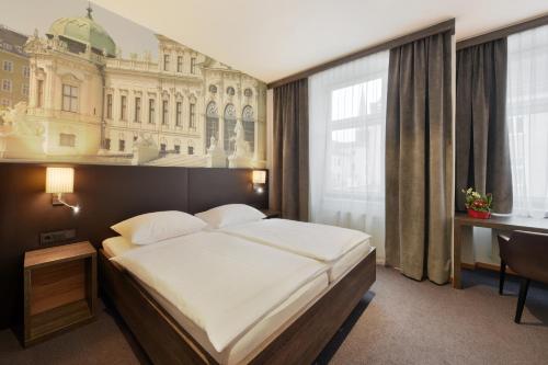 ウィーンにあるホテル ルチアのベッドとデスクが備わるホテルルームです。