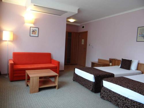 a hotel room with two beds and a red couch at Hotel Real in Plovdiv