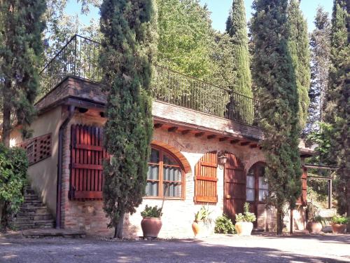an old stone house with a balcony and trees at Podere Mezzastrada - Place of Charme in Fiano