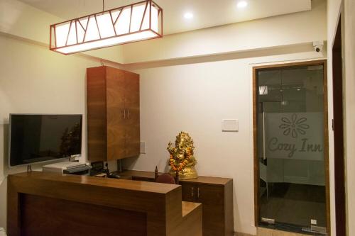 a living room with a tv and a tv stand at Hotel Cozy Inn in Pune