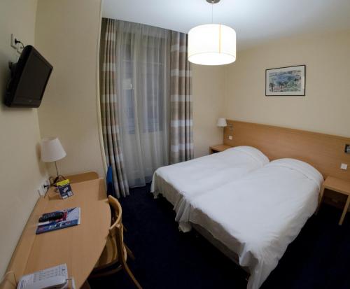 a hotel room with a bed and a desk and a tv at Hôtel du Nord in Annecy