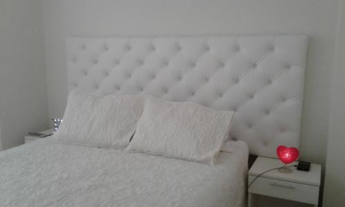 Una cama blanca con un gran cabecero acolchado blanco en Edificio California en Centro Historico, en Lima