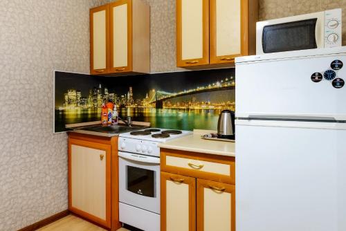 una cucina con piano cottura bianco e frigorifero di Apartment TwoPillows on Lomonosova 9 a Vorkuta