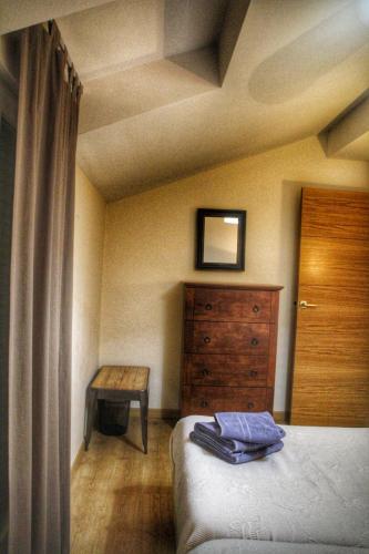 a bedroom with a bed and a dresser and a table at Apartamentos Alcazar de Baeza in Baeza
