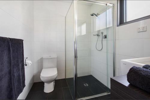 uma casa de banho com um WC e uma cabina de duche em vidro. em Latitude20 The Dunes em Karratha