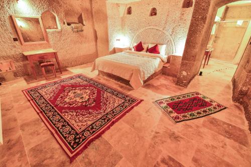 a bedroom with a bed and two rugs at Mosaic Cave Hotel in Göreme
