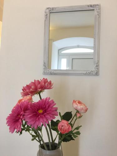 a vase with pink flowers in front of a mirror at B&B Bari Old Town in Bari
