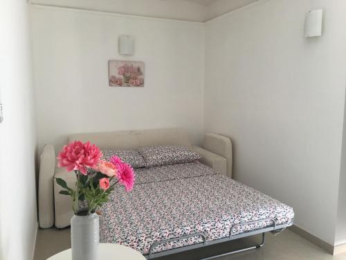 Un pequeño dormitorio con una cama y un jarrón con flores en B&B Bari Old Town, en Bari