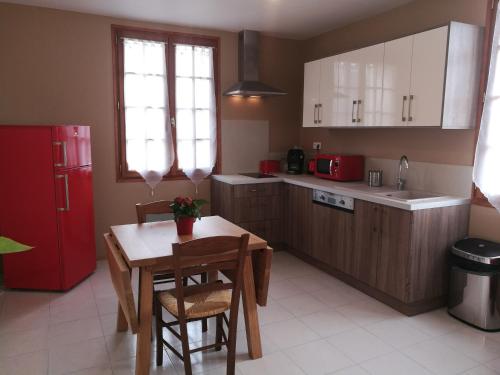 une cuisine avec une table et un réfrigérateur rouge dans l'établissement Les Petits Cléments, à Villars