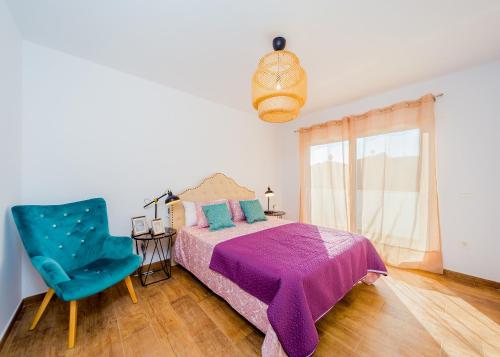 a bedroom with a bed and a blue chair at Apartamentos El Abuelo in Torrevieja