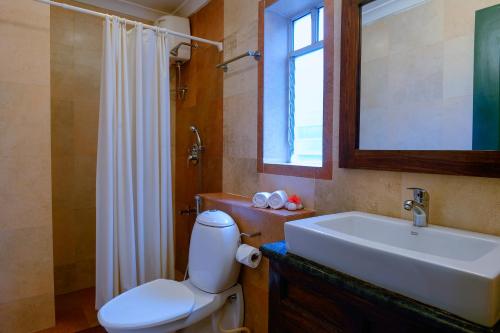 bagno con servizi igienici, lavandino e specchio di TreeHouse Blue Hotel & Serviced Apartments a Majorda
