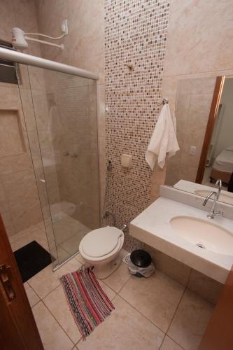 a bathroom with a shower and a toilet and a sink at Hotel Marina Torrano in Trindade
