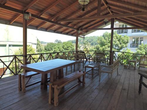 una terraza de madera con mesa y bancos. en Hotel Mango Garden, en Kandy