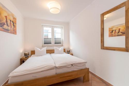 ein weißes Schlafzimmer mit einem Bett und einem Spiegel in der Unterkunft Villa Mona Lisa Whg. 5 in Göhren