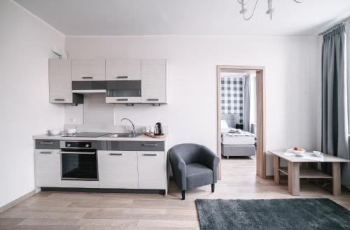 una cocina con armarios blancos, una silla y una mesa en Apartamenty 1 Maja 45, en Elbląg