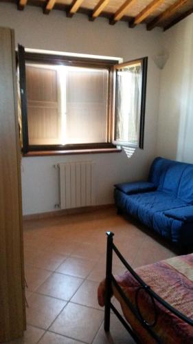 a living room with a blue couch and a window at Podere Mammoleta in Fattoria Marsiliana