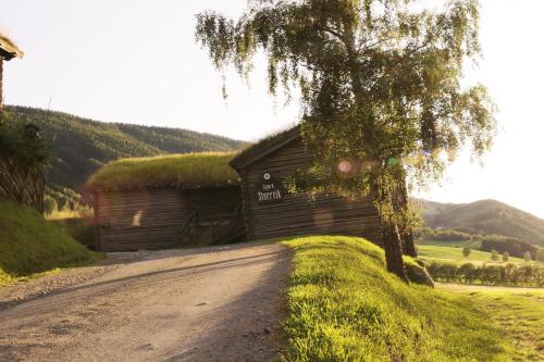 a barn with a tree next to a dirt road at Sygard Storrvik in Storrvik