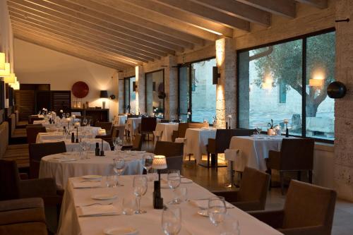 a dining room with white tables and chairs and windows at Relais Histò San Pietro Sul Mar Piccolo in Taranto