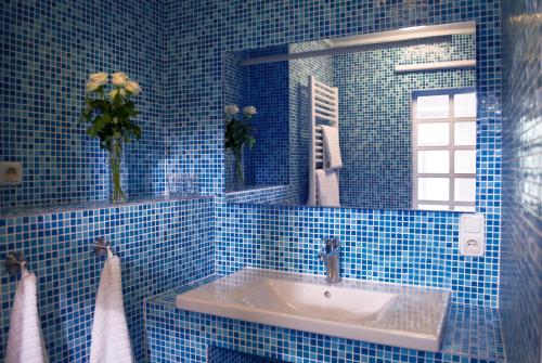 Baño de azulejos azules con lavabo y espejo en Gästezimmer der Adler Wirtschaft en Hattenheim