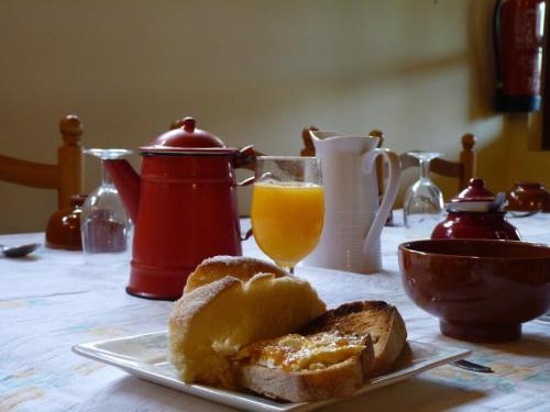 a table with a plate of bread and a glass of orange juice at Casa Pousadoira in Miño