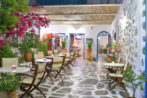 restauracja ze stołami, krzesłami i kwiatami w obiekcie Hotel Nazos w mieście Mykonos